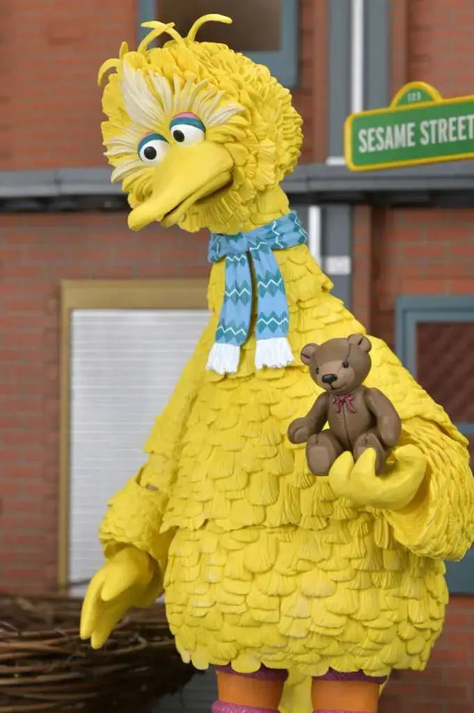 NECA Sesame Street Big Bird Ultimate action figure, yellow Big Bird holding a brown teddy bear with a blue scarf