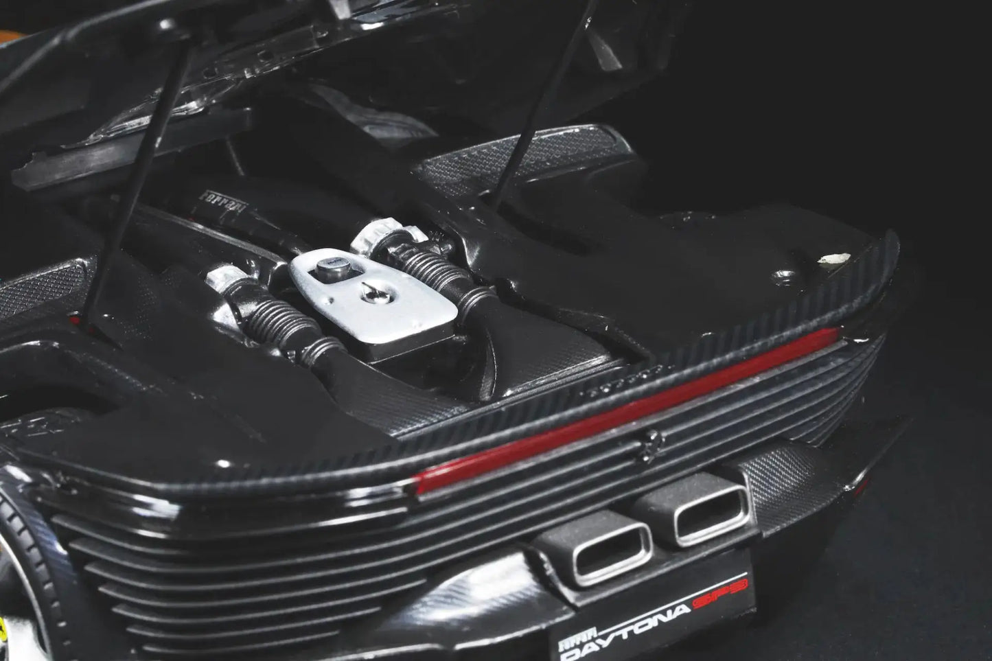 Ferrari Daytona SP3 1:18 diecast model in black carbon fiber finish with detailed engine bay and dual exhausts.