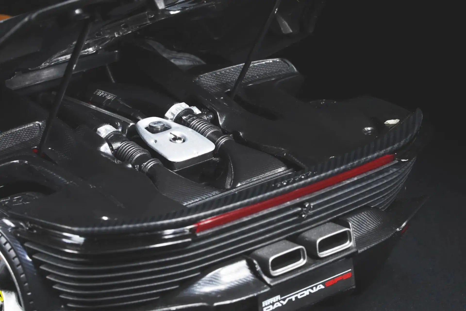Ferrari Daytona SP3 1:18 diecast model in black carbon fiber finish with detailed engine bay and dual exhausts.