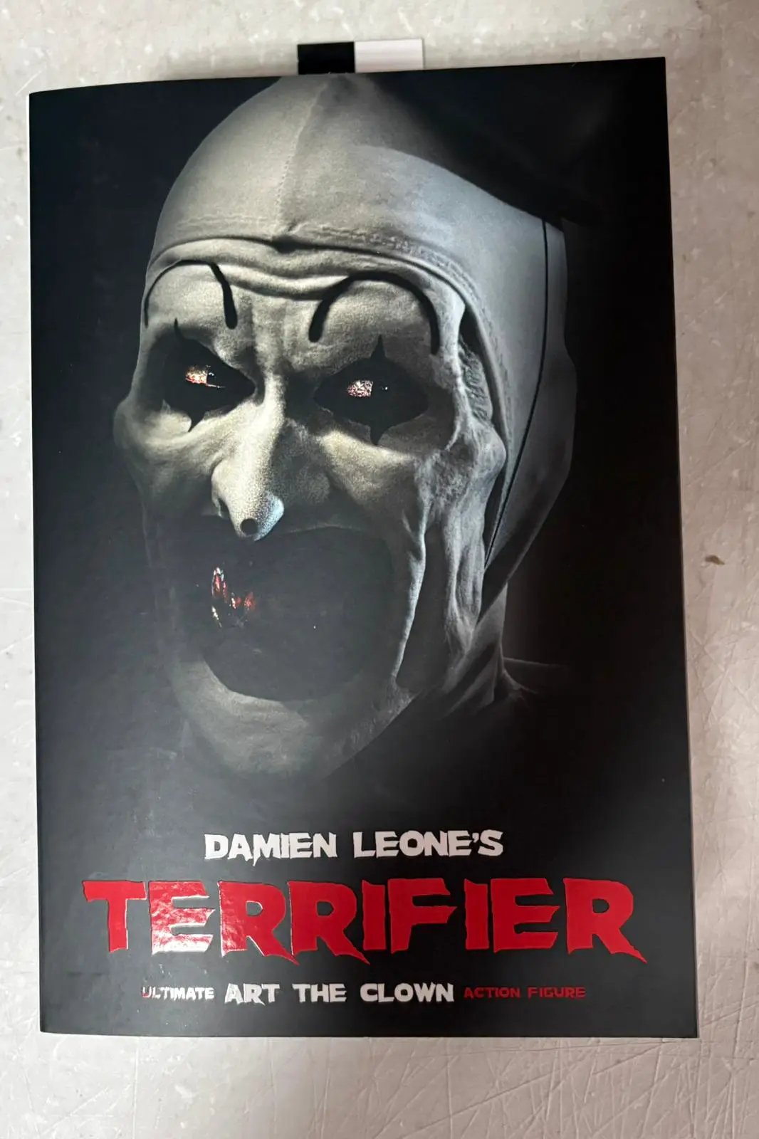 Terrifier Figura 17 cm action figure by NECA, box featuring a pale, sinister clown head.