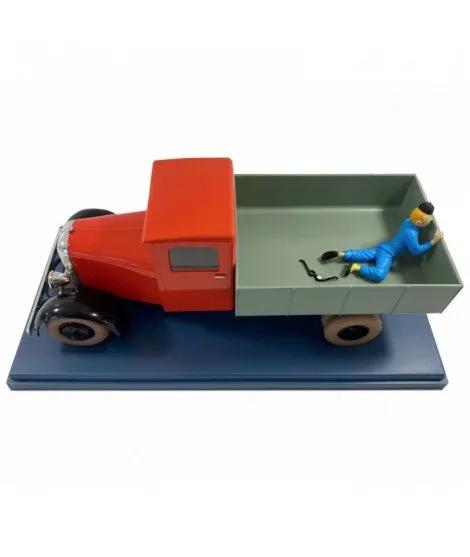 MOULINSART Tintin 1/24 scale red truck model with gray cargo bed on blue display base; figure in blue in bed