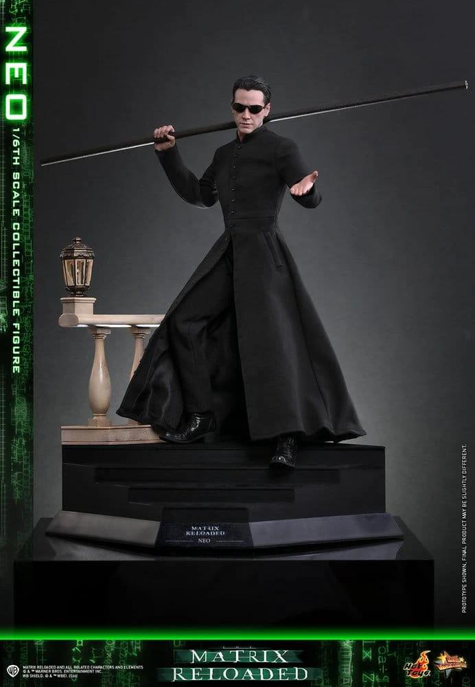 Hot Toys Matrix Neo 1/6 scale action figure in black trench coat with sunglasses, holding a long staff on display base.