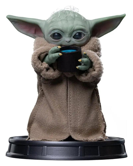 Grogu collectible statue by IRON STUDIOS; green head, beige robe, holding blue cup on black base