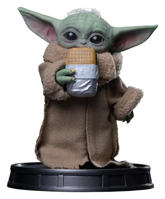 IRON STUDIOS Grogu statue from The Mandalorian, holding a wrapped waffle snack on a black display base