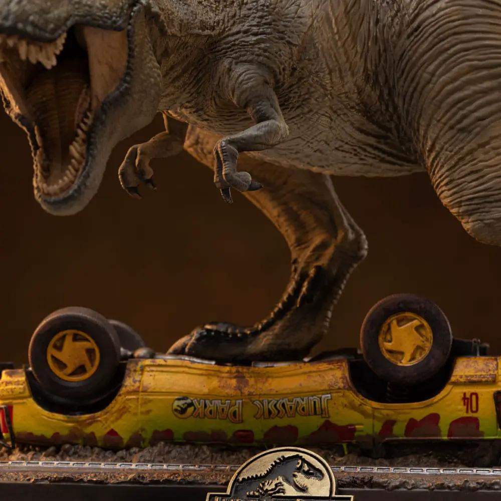 Figura Estatua T-Rex Attack de Jurassic Park Icons, 15 cm, sobre un coche amarillo con logo de Jurassic Park.