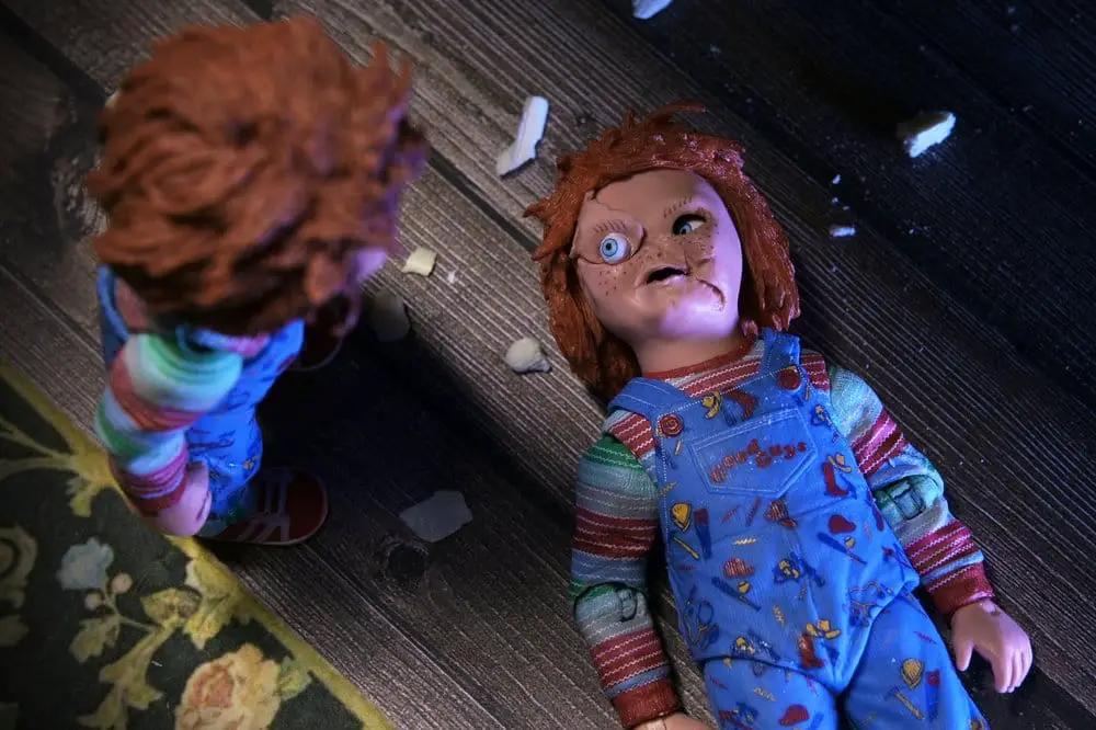 Figura NECA Chucky Ultimate 18 cm con dos figuras de acción de Child's Play 2 en un suelo de madera, una con overol azul.
